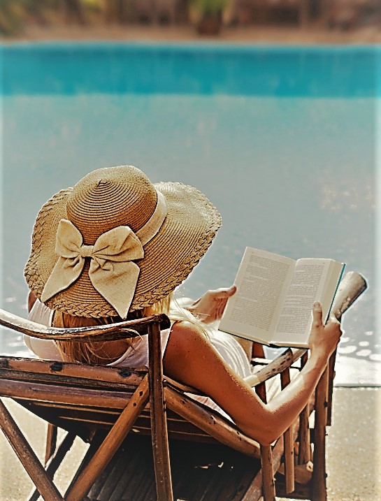 woman reading and relaxing near luxury swimming pool